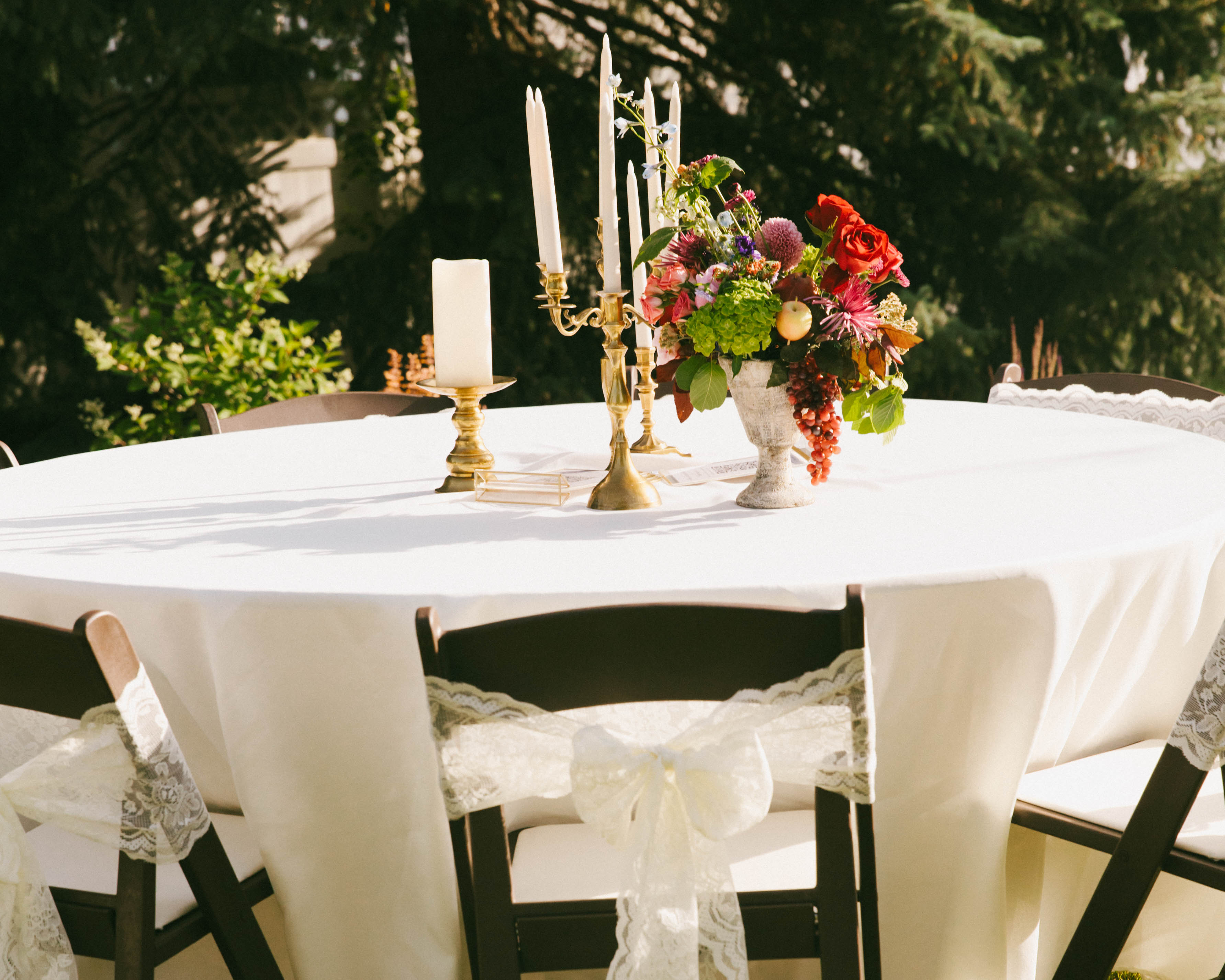 Ivory lace bow tied on a dark wood folding chair at an outdoor wedding reception