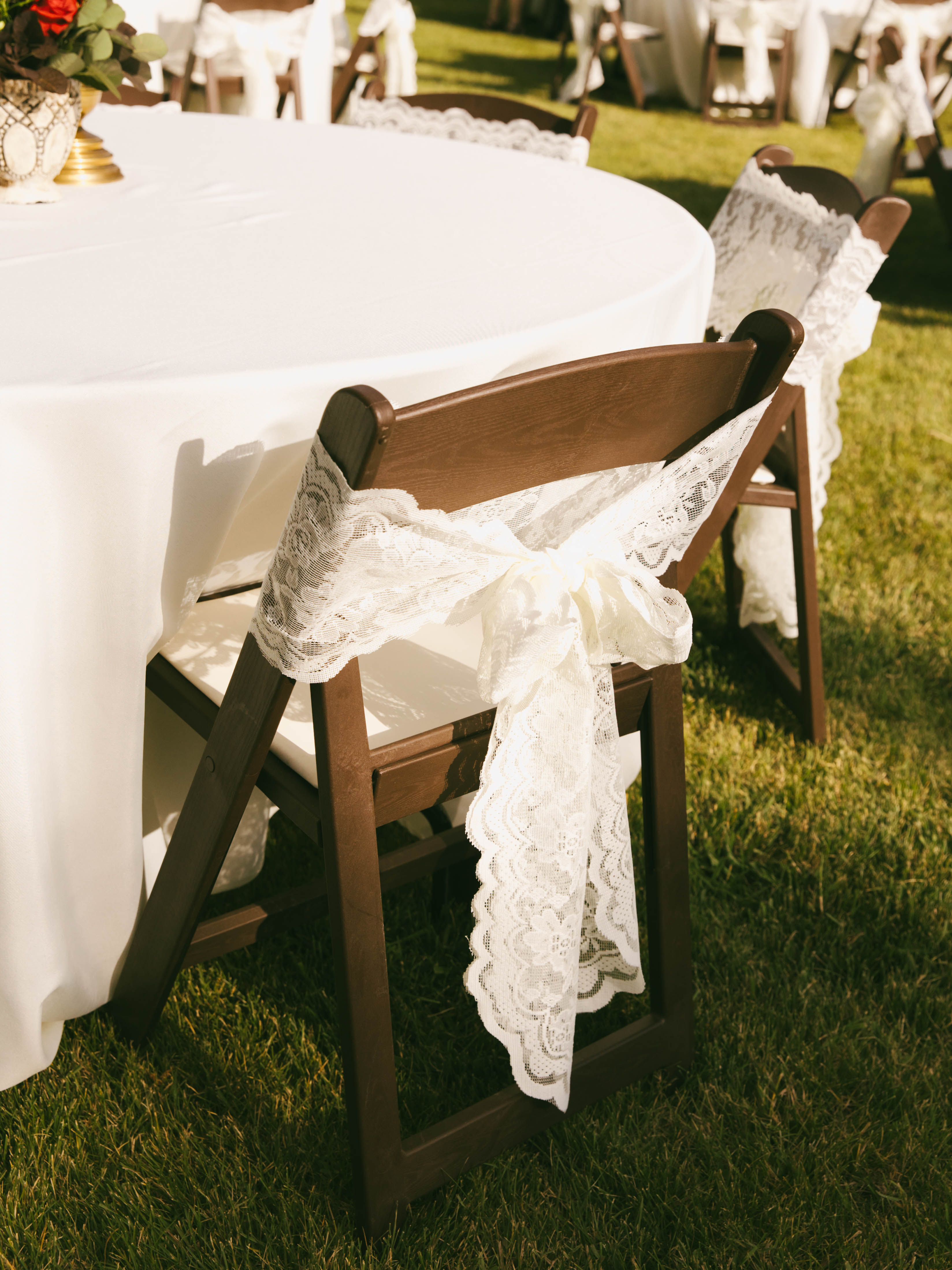 Outdoor wedding venue with multiple tables decorated with ivory lace bows
